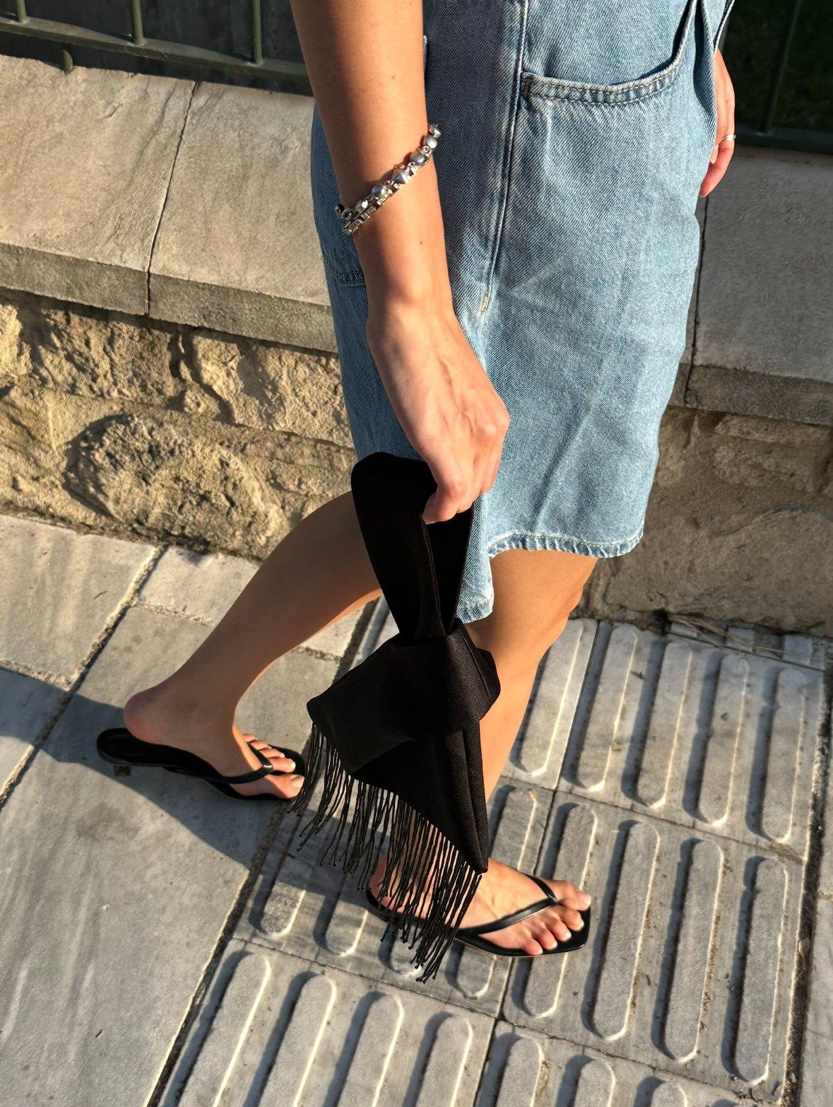 Noir satin bag carried in afternoon light